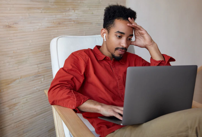Man using his laptop confused by how he suddenly stopped getting likes on Tinder
