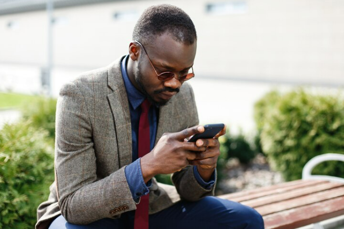 Young african man seated wondering whether Hinge bans device 